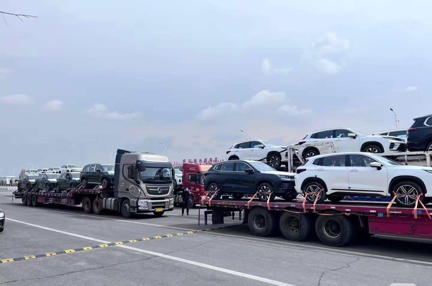 SUVs loaded on flatbed trailers for port delivery