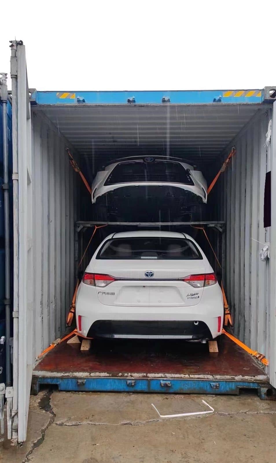 Two vehicles loaded on two tiers inside a container