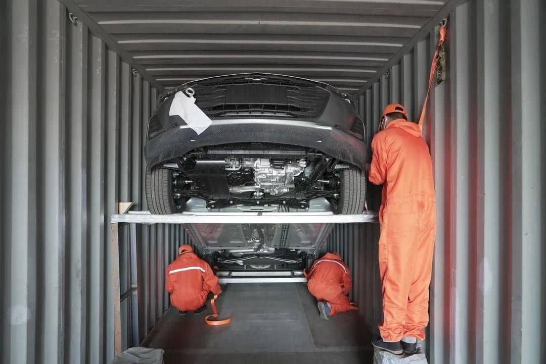 Workers lashing a vehicle inside a shipping container